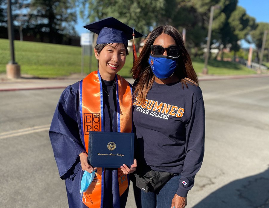 EOPS student in graduation cap and gown standing with EOPS supervisor