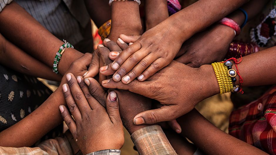 Photo of children's hands in circle showing unity