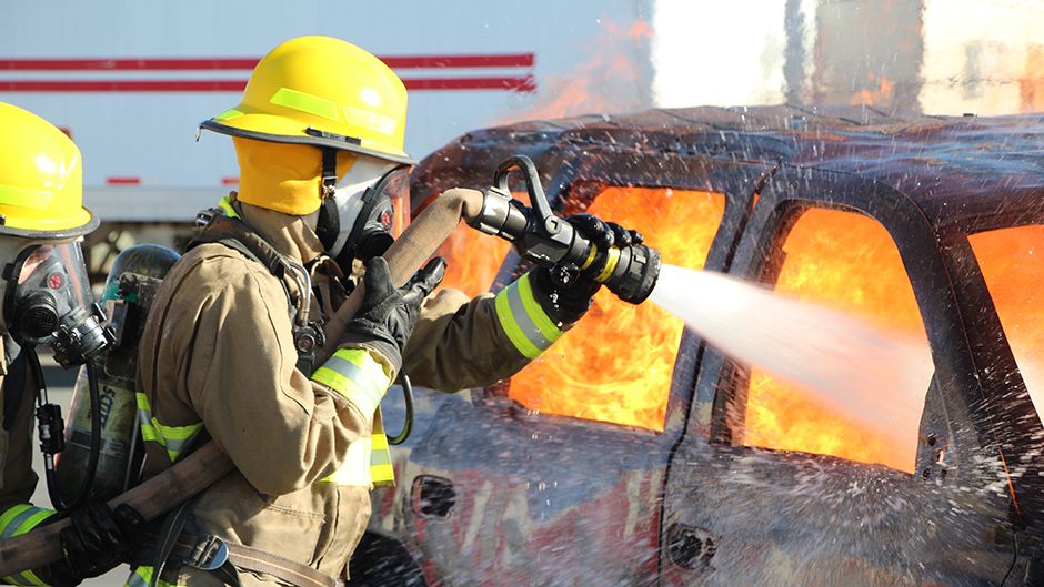 Firefighters in training putting out a car fire