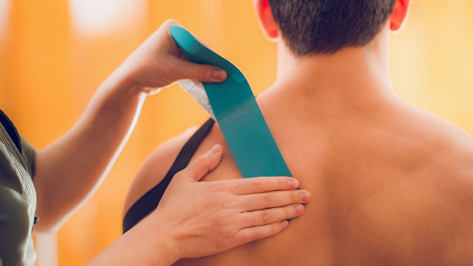 Kinetic tape being applied to a bare shoulder