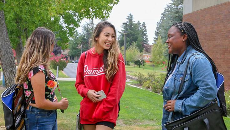 Three students talking together on campus