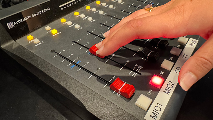 A hand sliding a control on a production board