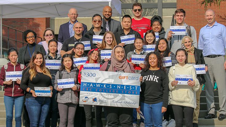 Scholarship winners holding a large banner on the college steps