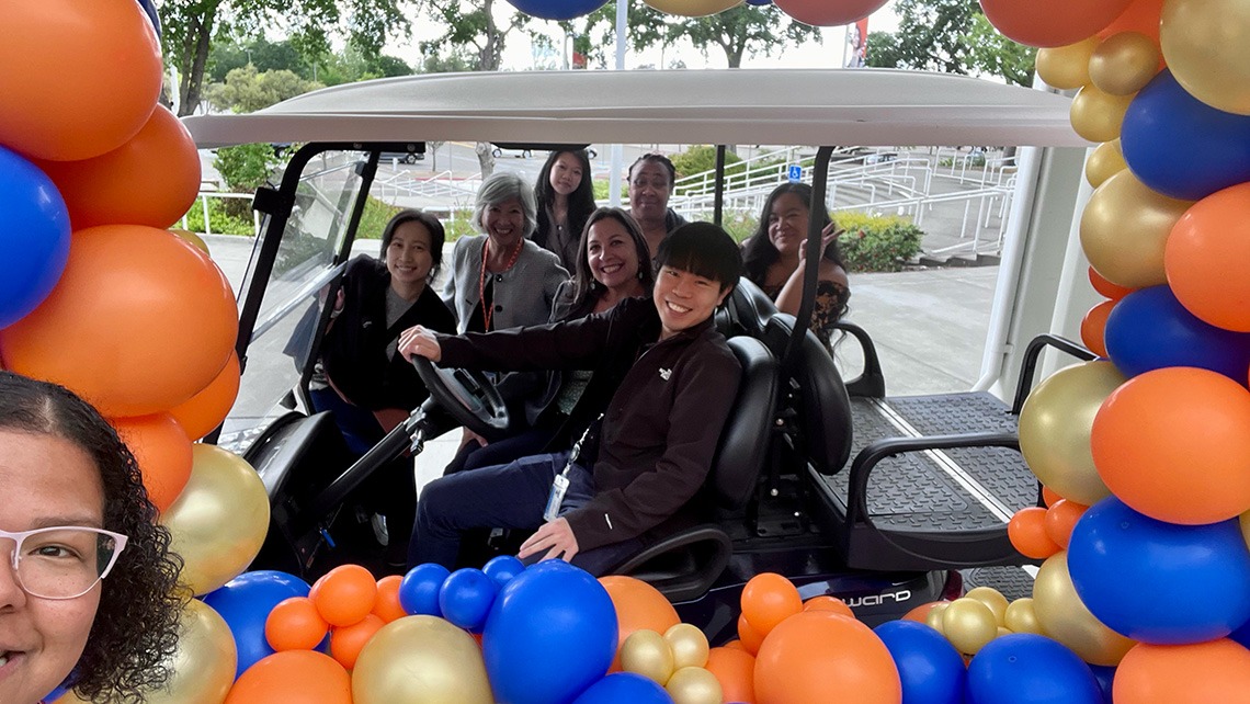 Care team riding in a golf cart surrounded by balloons