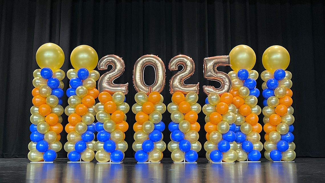 Colorful balloon columns on stage with number balloons spelling 2025