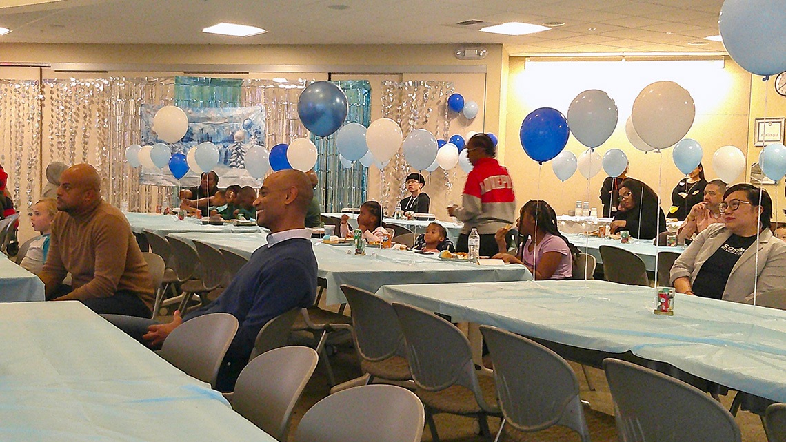 Students and staff in a meeting room decorated for a celebration