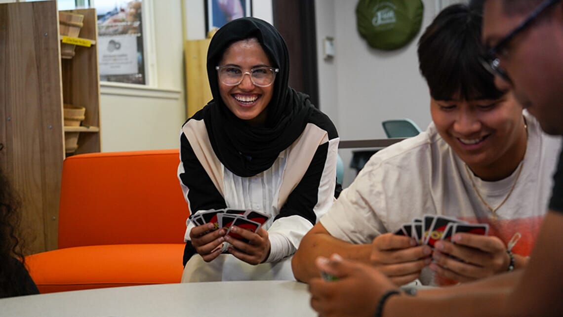 A student playing a game of Uno with other students