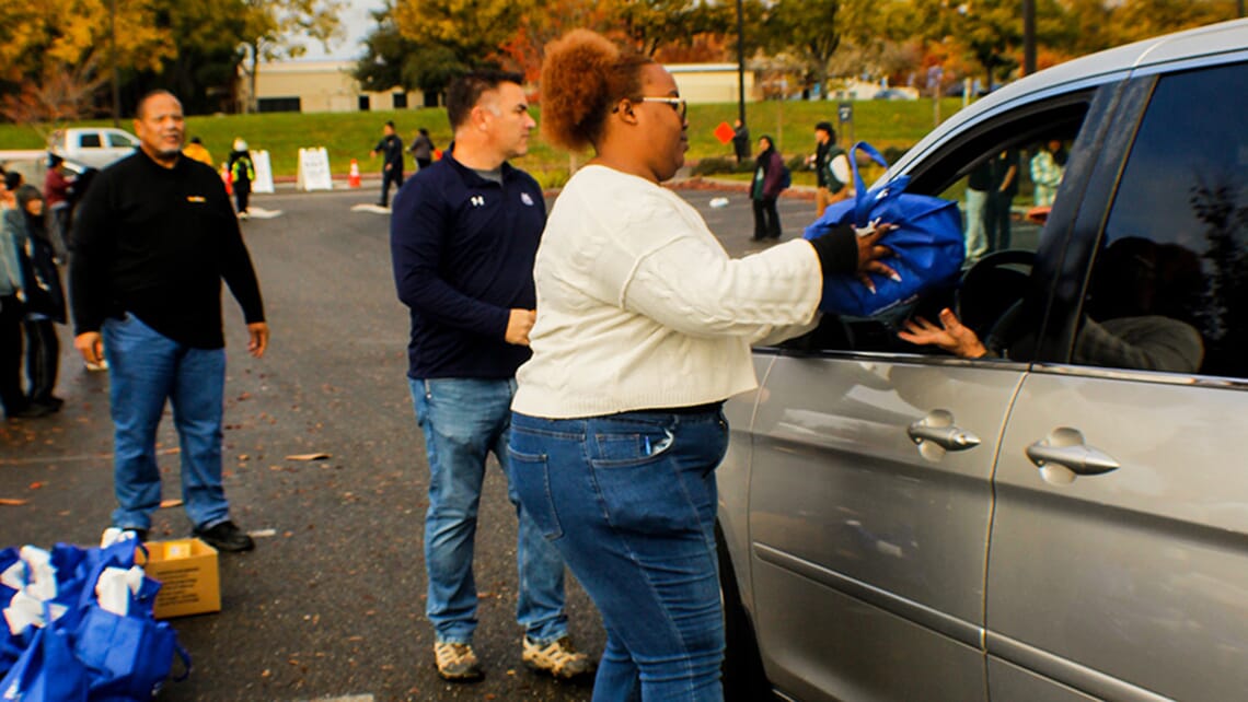 A drive-through event organized by the Hawk CARES Center; a woman handing food through a car window