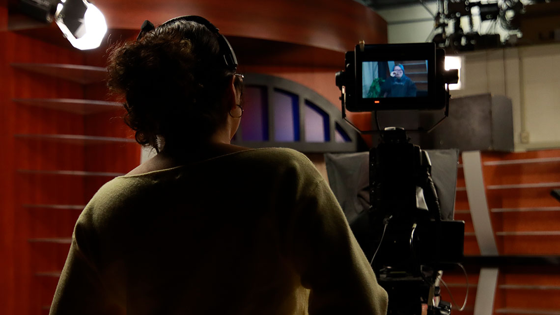 The back view of a person operating a video camera