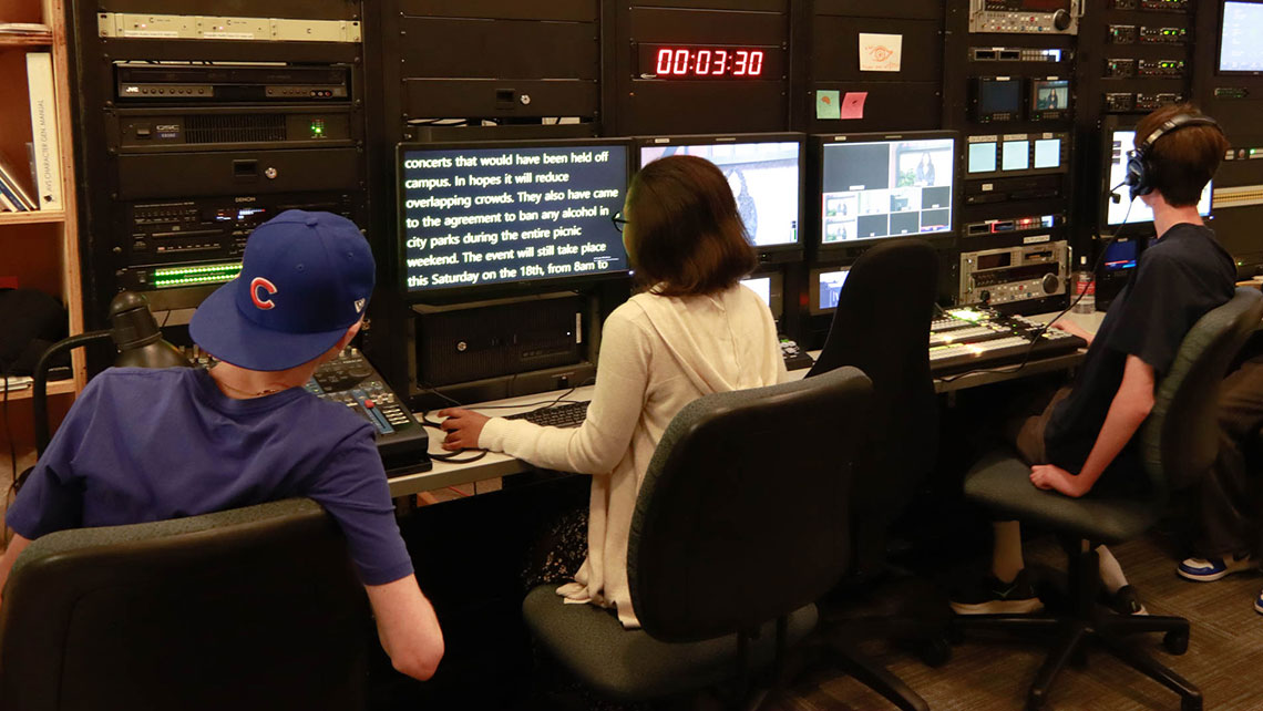 A team of students at a production desk, looking at monitors
