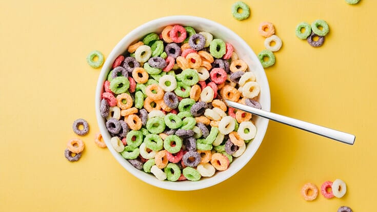 A bowl of colorful fruity cereal on a yellow background