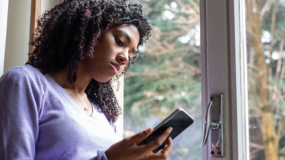 A photo of a woman looking at her phone sadly