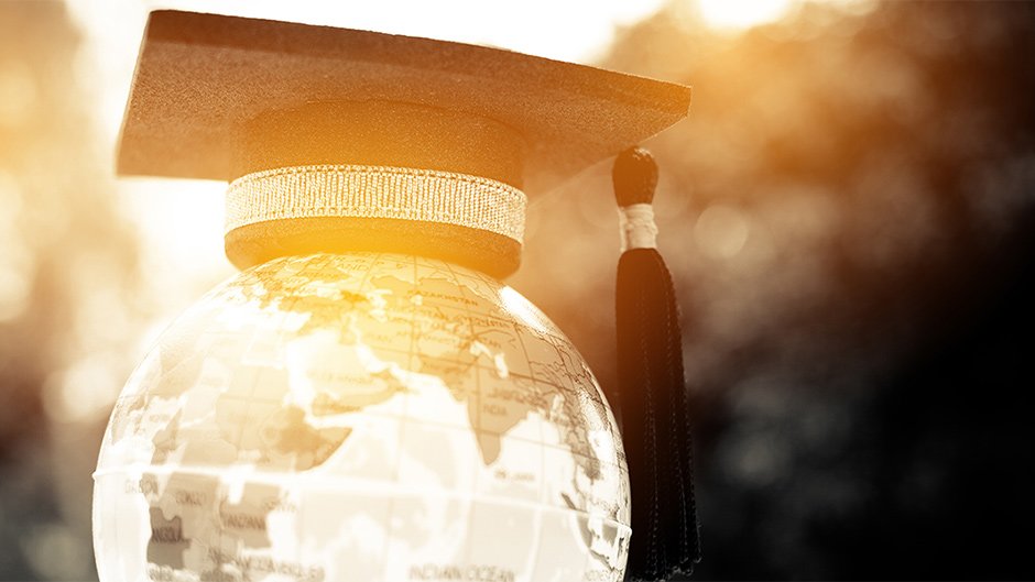 Glass globe and graduation cap with sun shining through