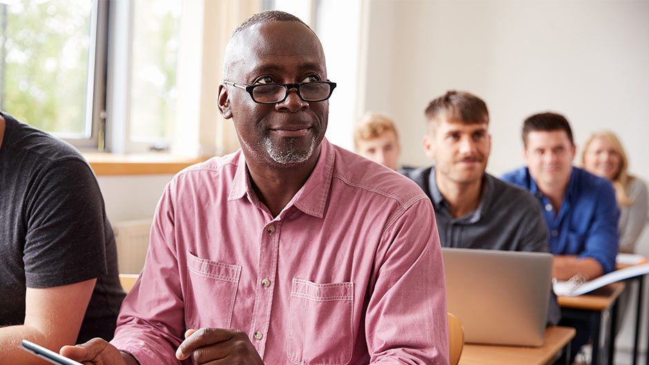 A middle-aged Black man sitting in a classroom