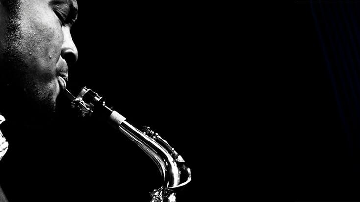 Black and white close-up photo of a man playing a saxophone