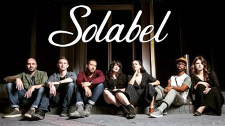 The members of Solabel sitting on the ground with the word Solabel above